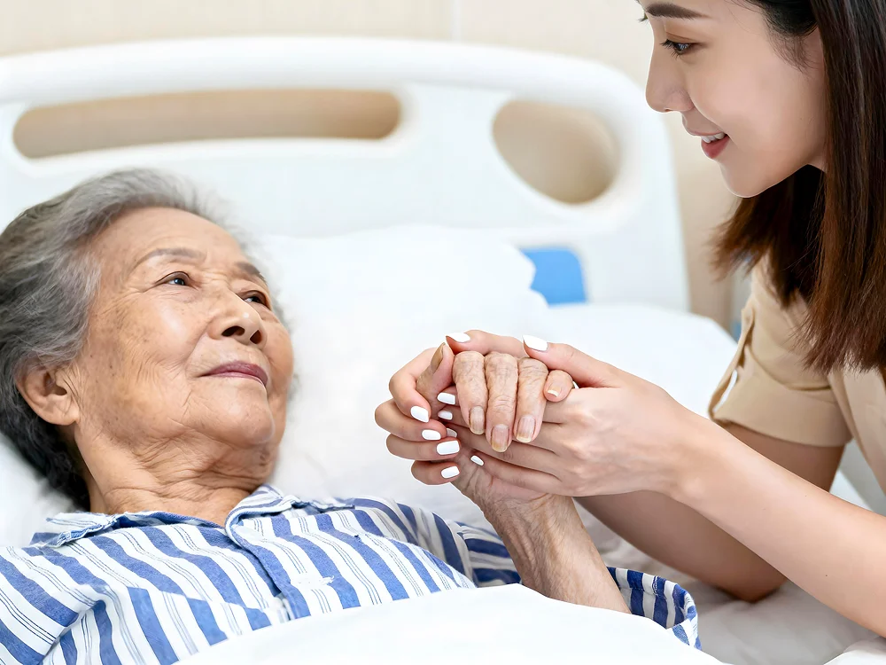 대구 암요양병원 픽업|병원 침대에 누운 노인 환자를 위로하는 젊은 여성